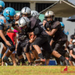 Raiders Peter Mesa drives the ball forward as Angels Josiah Mendiola looks to make the tackle. (Photo by Michael Blas)