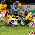 FD Friars Evan Brown (18) and Roy Chargualaf (54) slip through the Dolphins offensive line for a tackle on Conan Baza. (Photo by Michael Blas)
