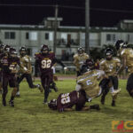 JFK's Justin Camacho goes airborne from the defenders tackle while Fd's Eugene Arriola finds the dirt (photo by Michael Ebio)