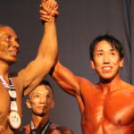 Competitor Taharu Kiyomtisu shares his medal with long time body builder Jason Cruz on stage. (photo by Robert Balajadia)