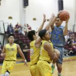 Jericho Perez (4) of the St. Paul Warriors goes up with the ball against Leon Shimizu (left) and Vince Leon Guerrero (right) of the Father Duenas Friars.(photo by Raine Delos Reyes)