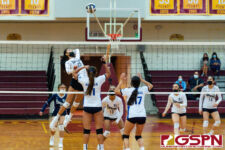 Academy Cougar Kristen Serrano leaps up for a kill against ND Royal Austia Mendiola and Gia Camacho. (Photo by Michael Blas)